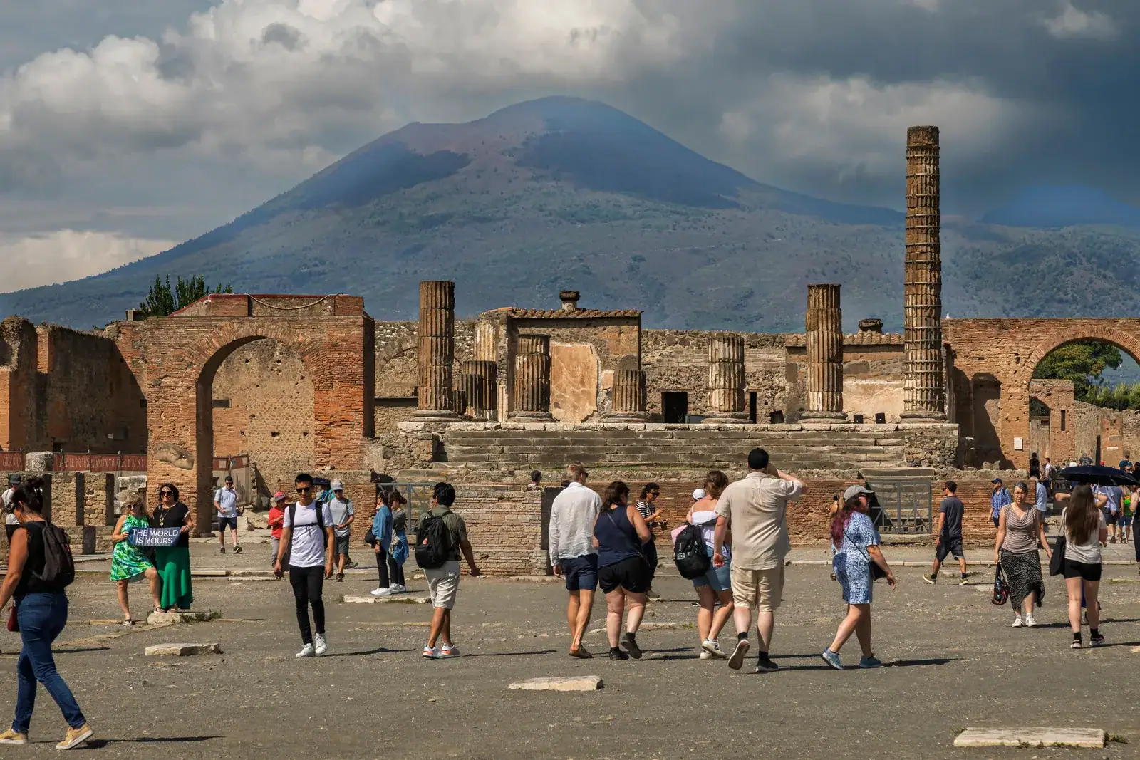 Látogatók Pompeji romjai között, háttérben a Vezúvval