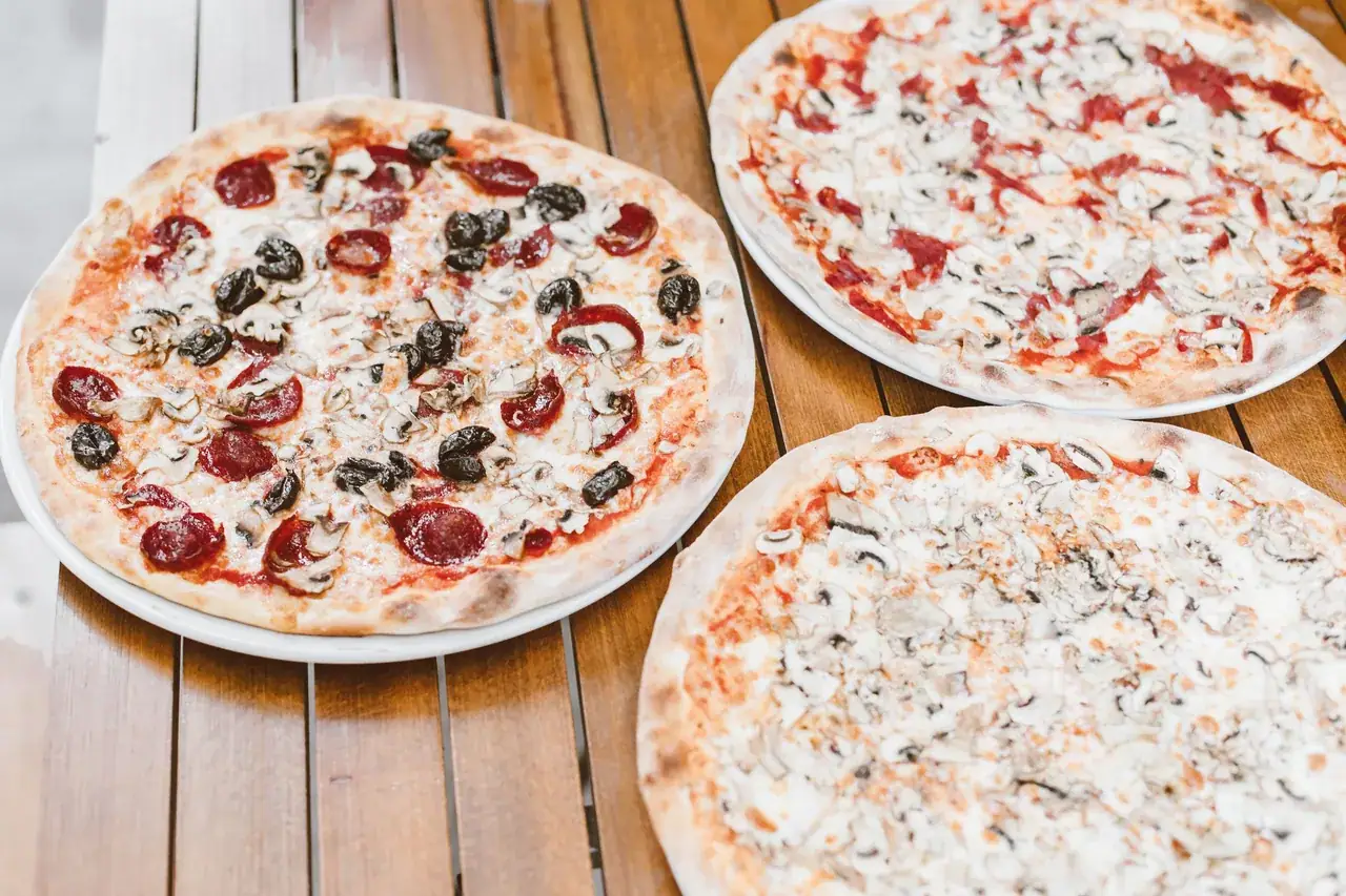 Többféle pizza egy fa asztalon